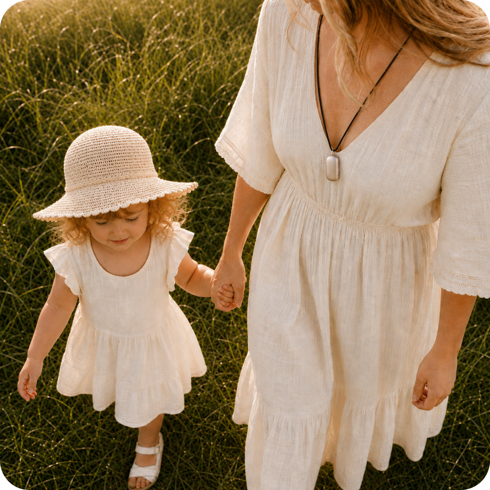 A parent and child walking through sunlit grass